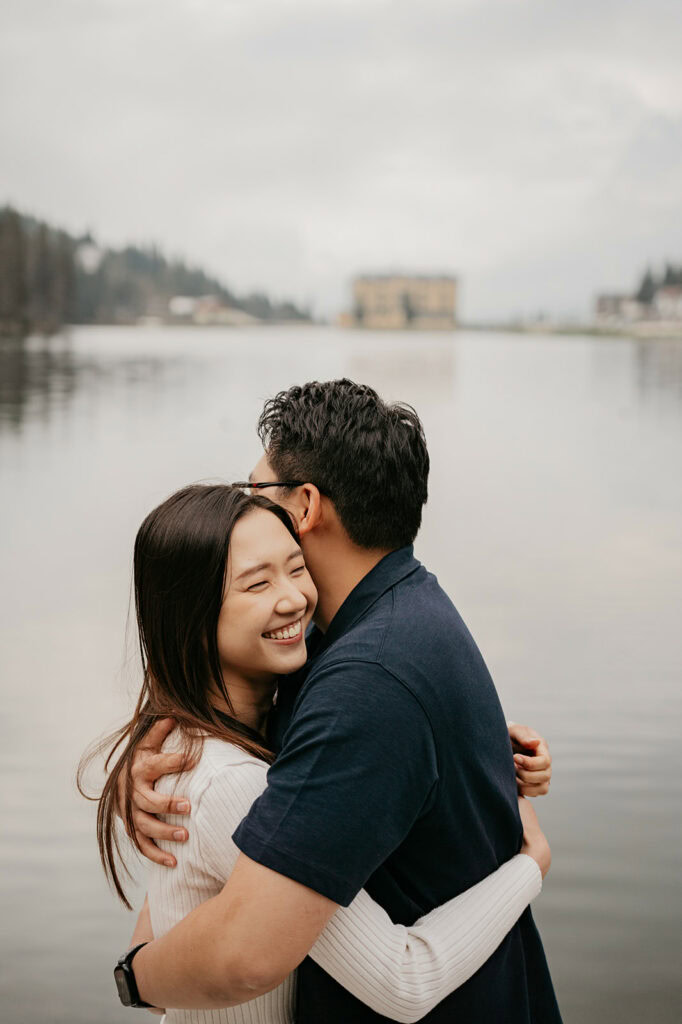 Smiling couple hugging by a serene lake