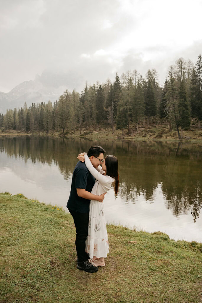 Couple embracing by a serene lakeside forest
