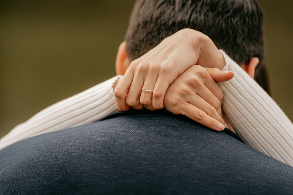 Hands with ring embracing partner's back.