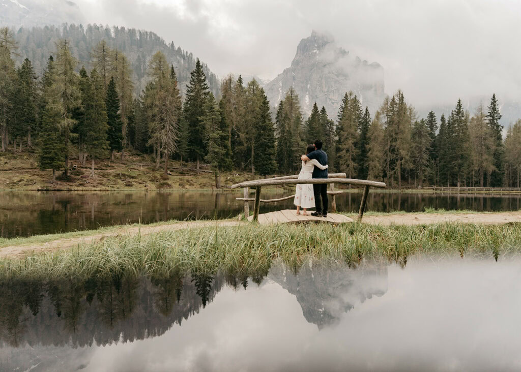 Couple embracing by a serene mountain lake.