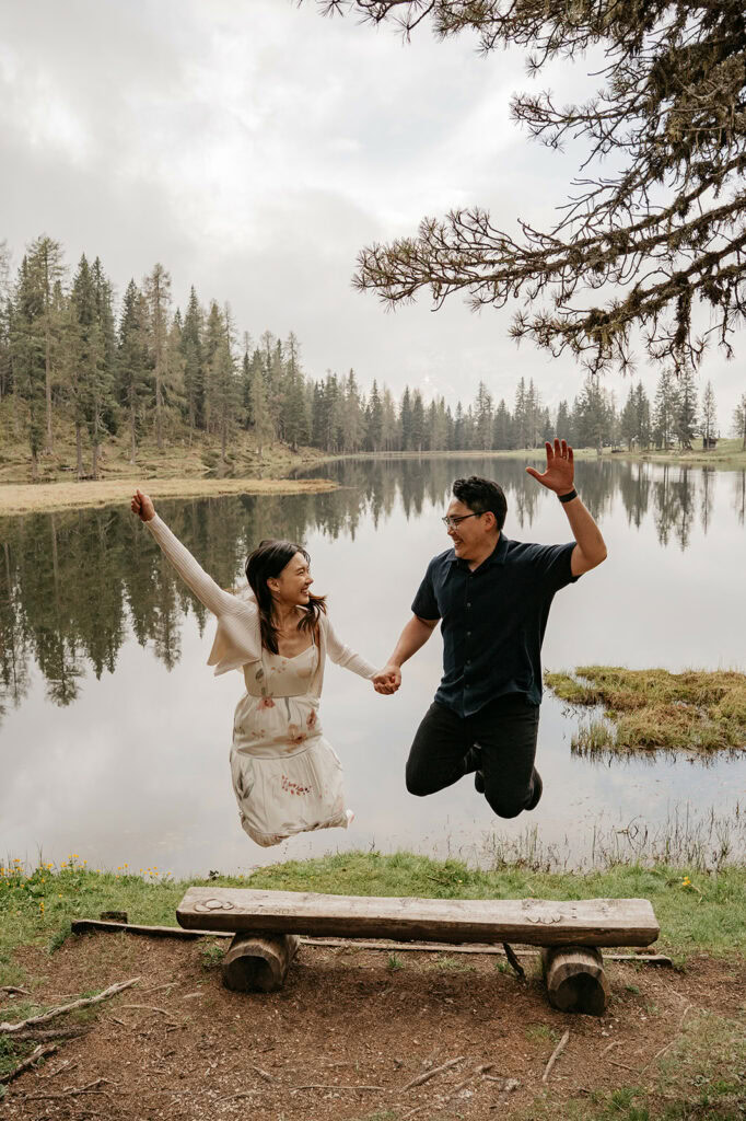 Couple jumping by lake in forest