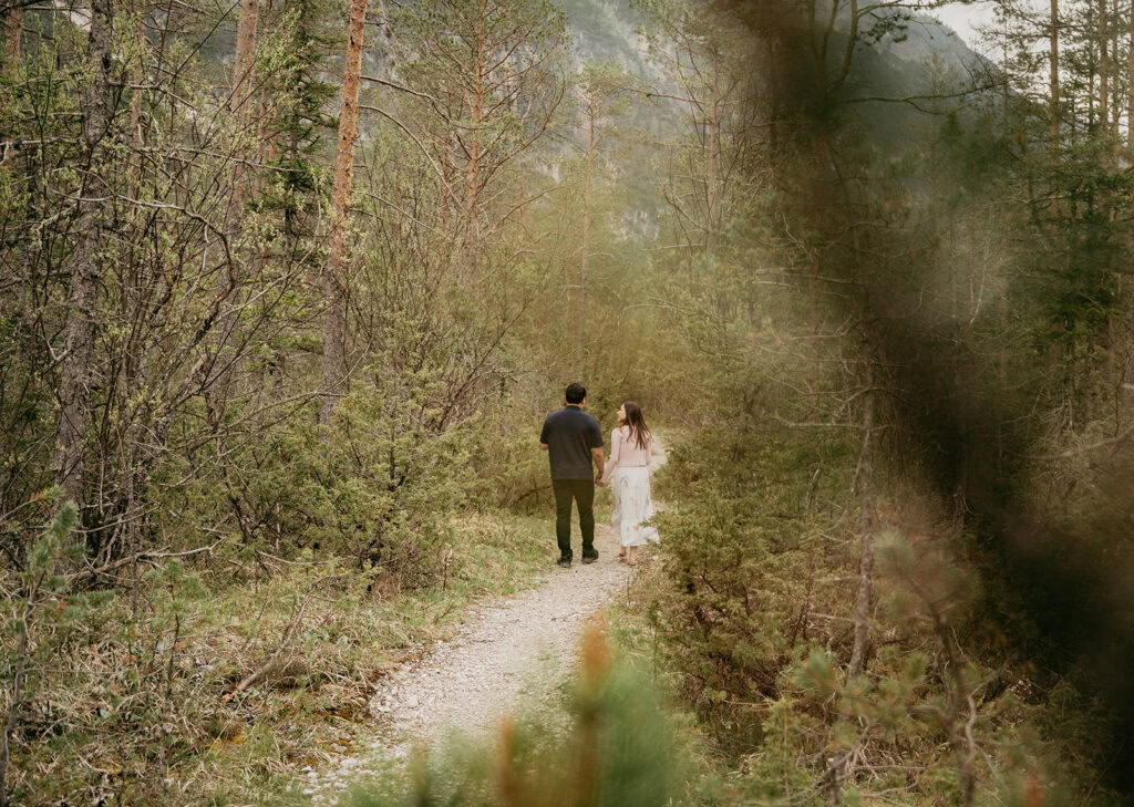 Couple walking on forest path hand in hand.