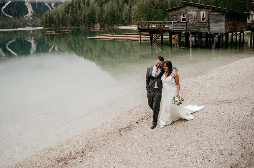 Bride and groom walking by lakeside cabin.
