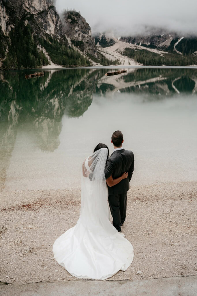 Bride and groom by mountain lake, scenic view.