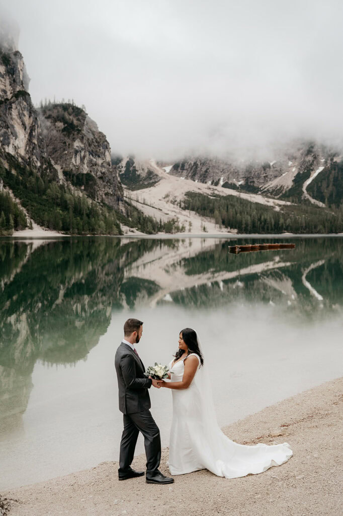 Couple wedding by mountain lake with misty reflections.