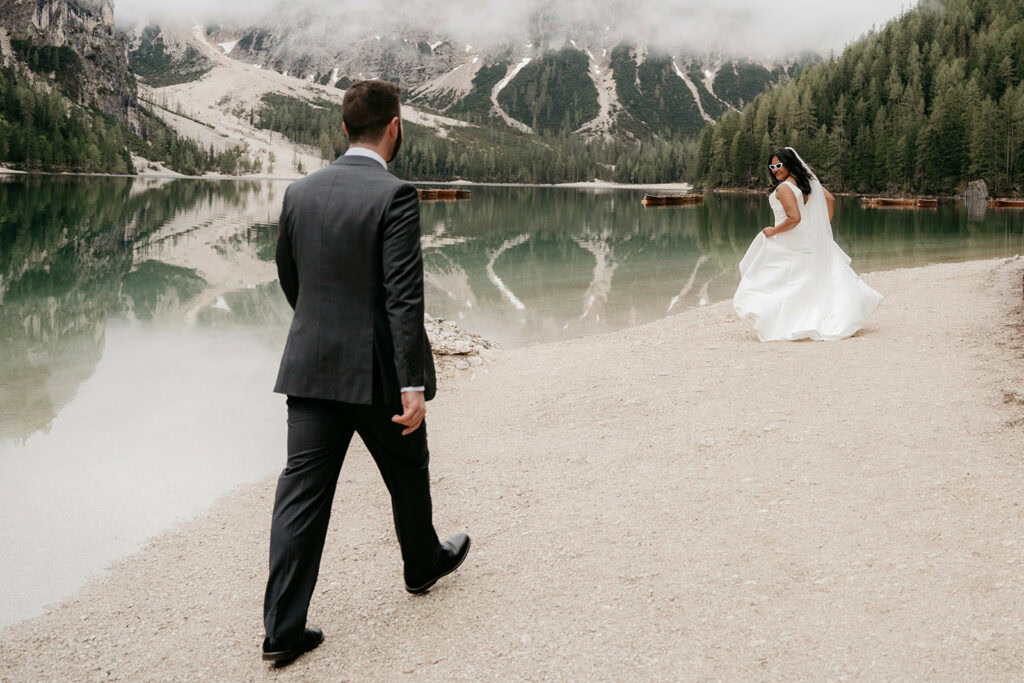Bride and groom walking by scenic lake.