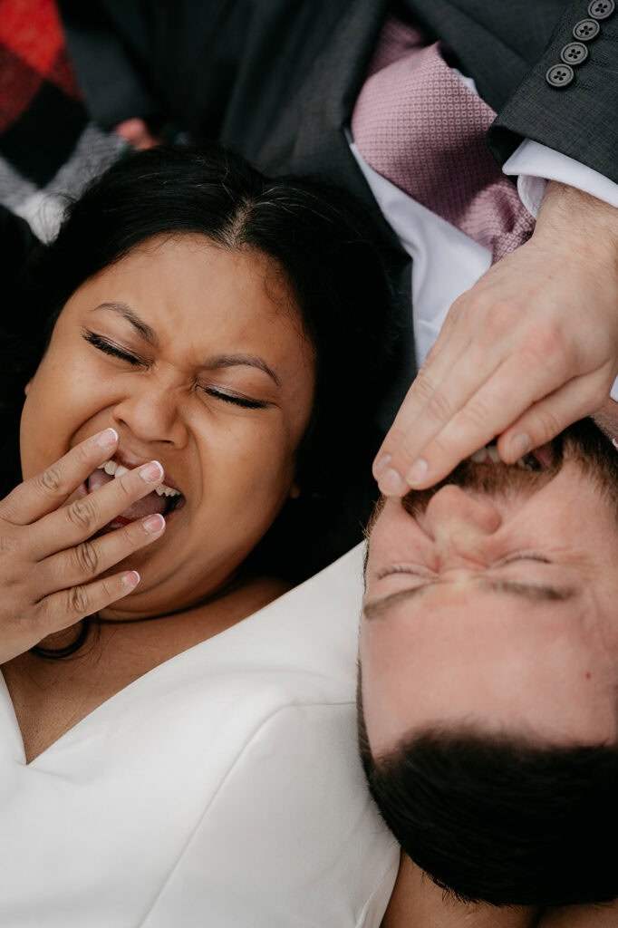 Laughing couple laying side by side outdoors.