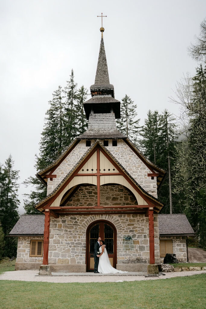 Stone chapel with couple, surrounded by trees