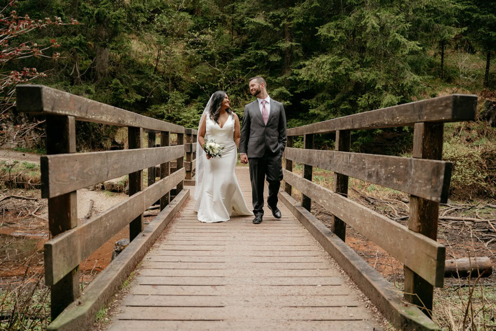 Bride and groom walking on a wooden bridge.