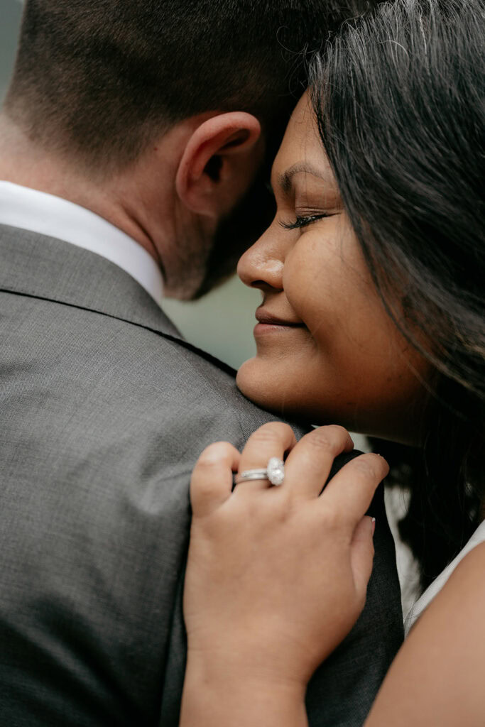 Close-up of couple embracing, showing engagement ring.