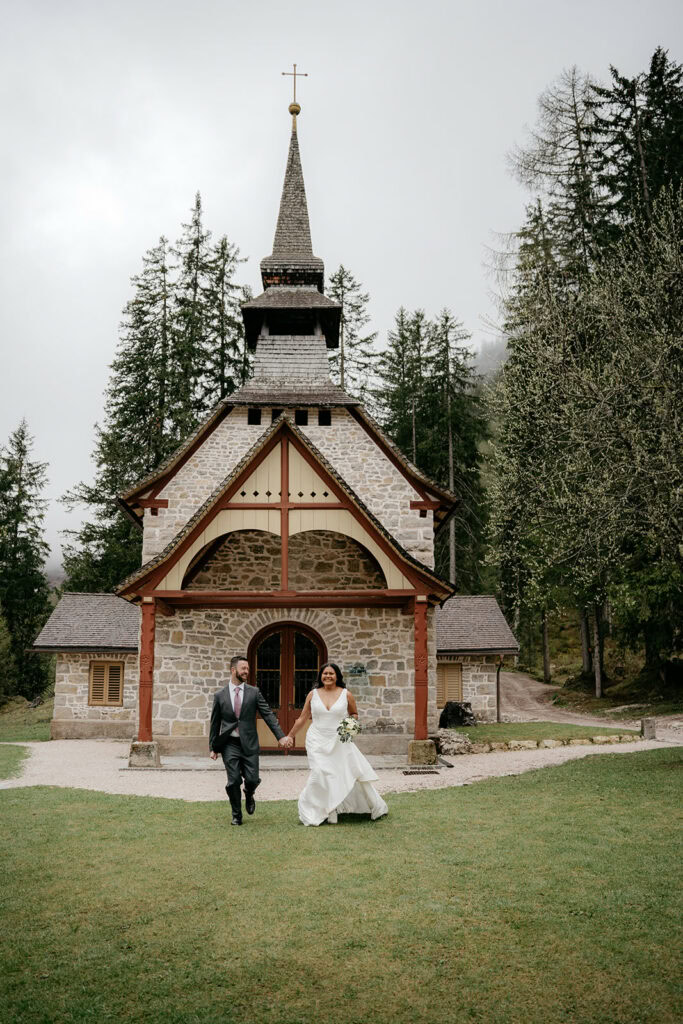 Bride and groom walking outside stone church