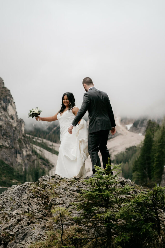 Bride and groom on mountain, foggy background.