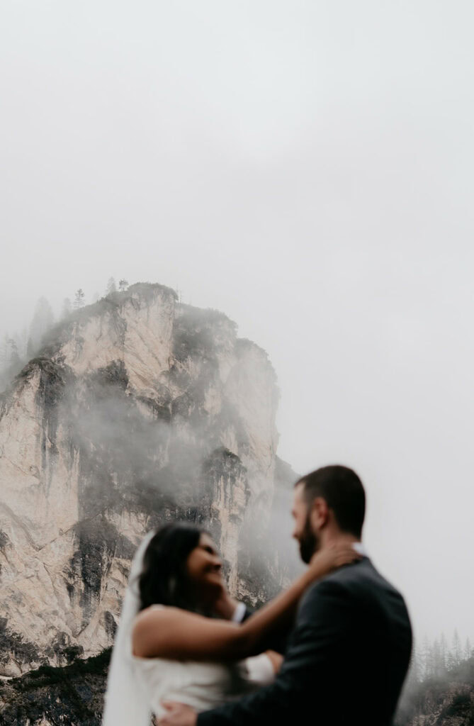 Couple embraces with misty mountain backdrop.