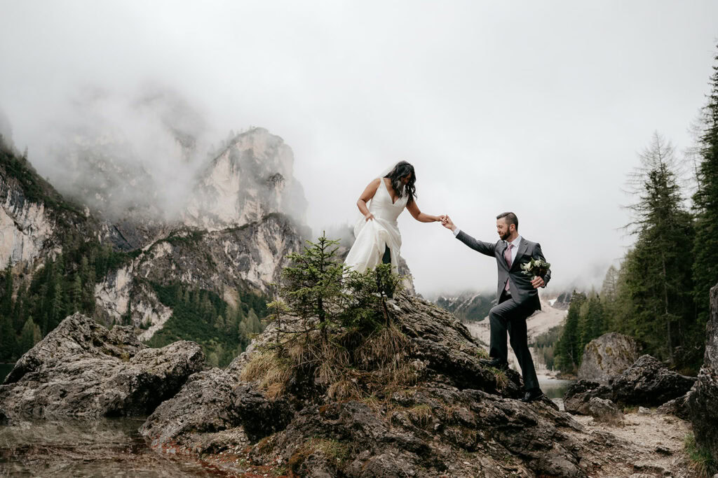 Couple in wedding attire on rocky mountain landscape.