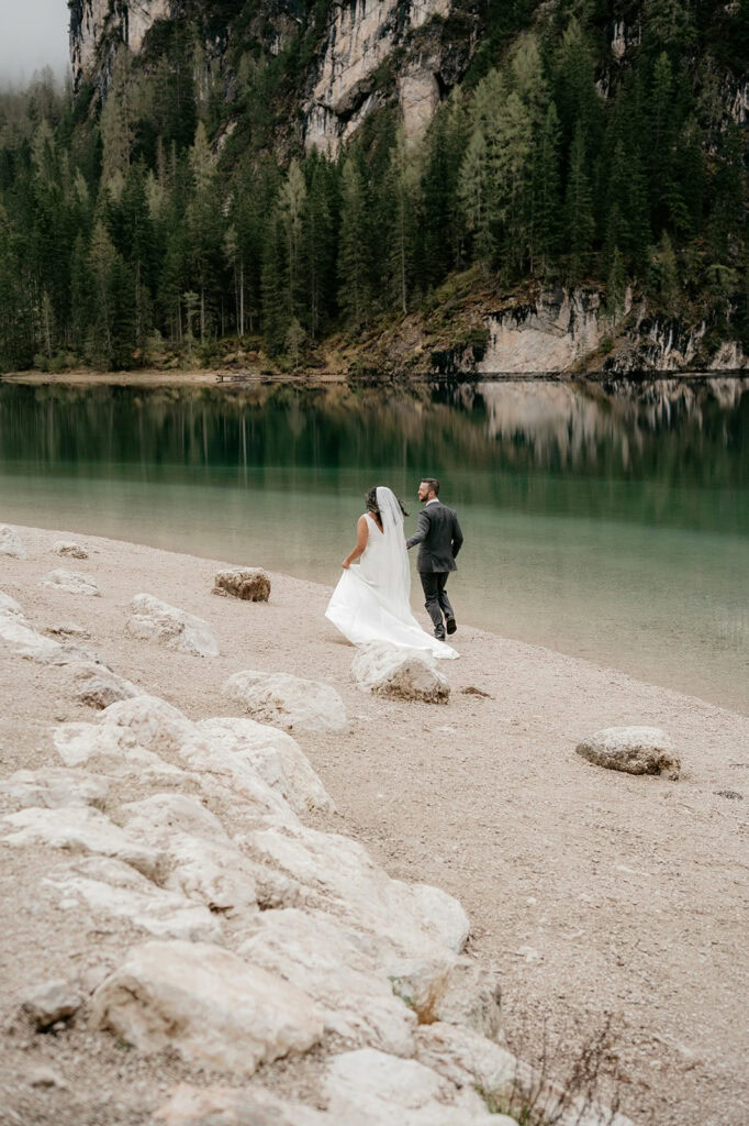 Bride and groom walking by a serene lake.