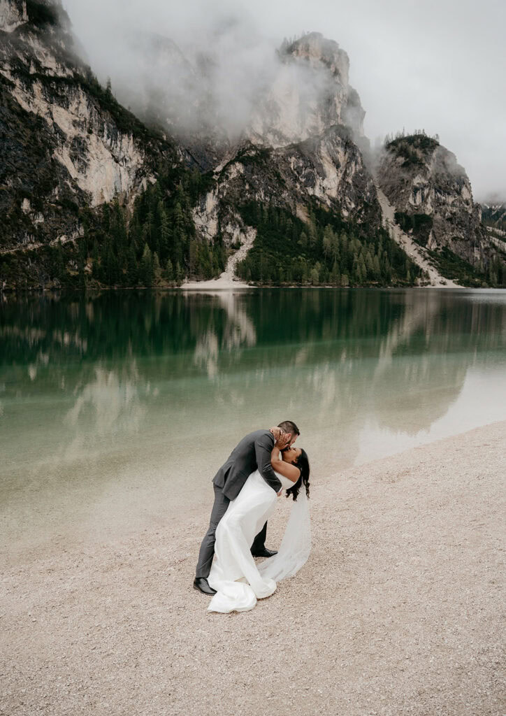 Couple kissing by a serene mountain lake.