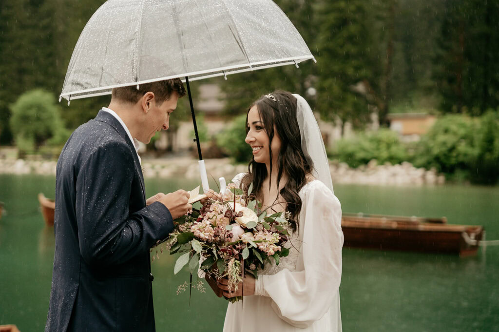 Bride and groom sharing vows under umbrella.