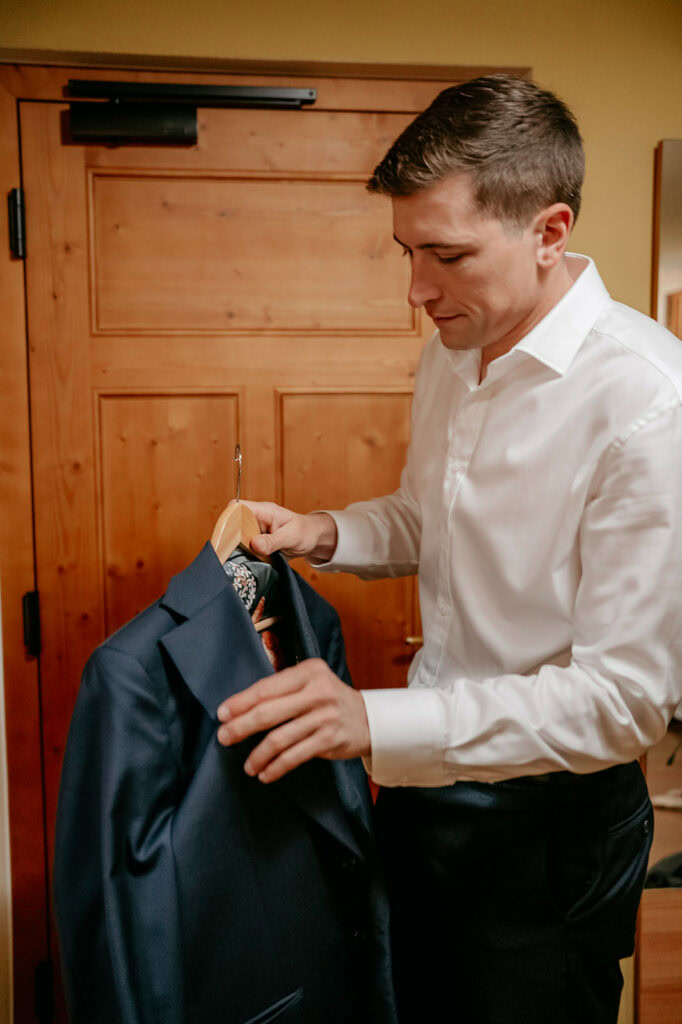Man in white shirt holds dark suit jacket.
