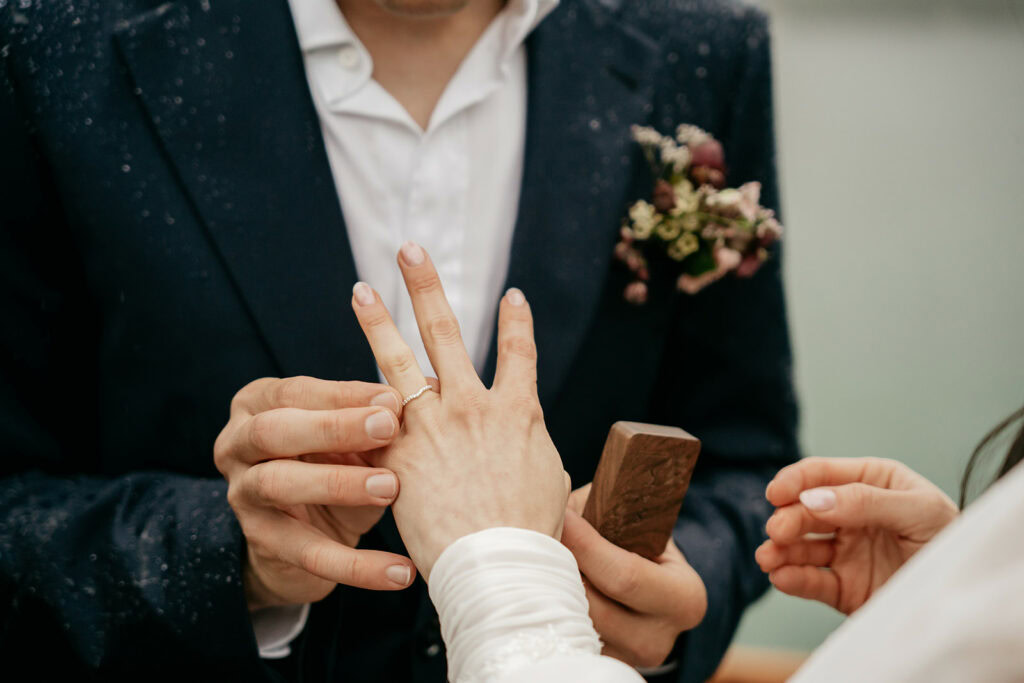 Groom placing ring on bride's finger during ceremony.