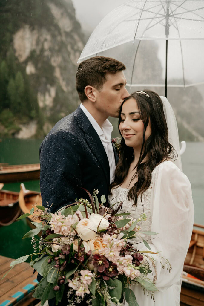 Bride and groom under umbrella with bouquet