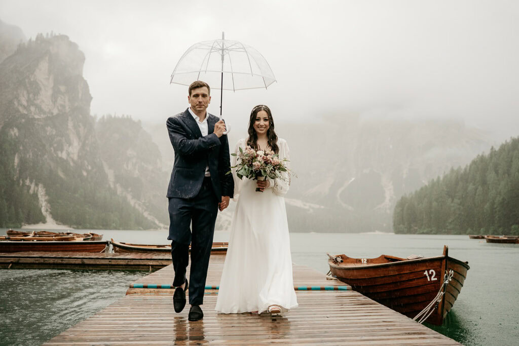 Couple walking on rainy dock with umbrella.