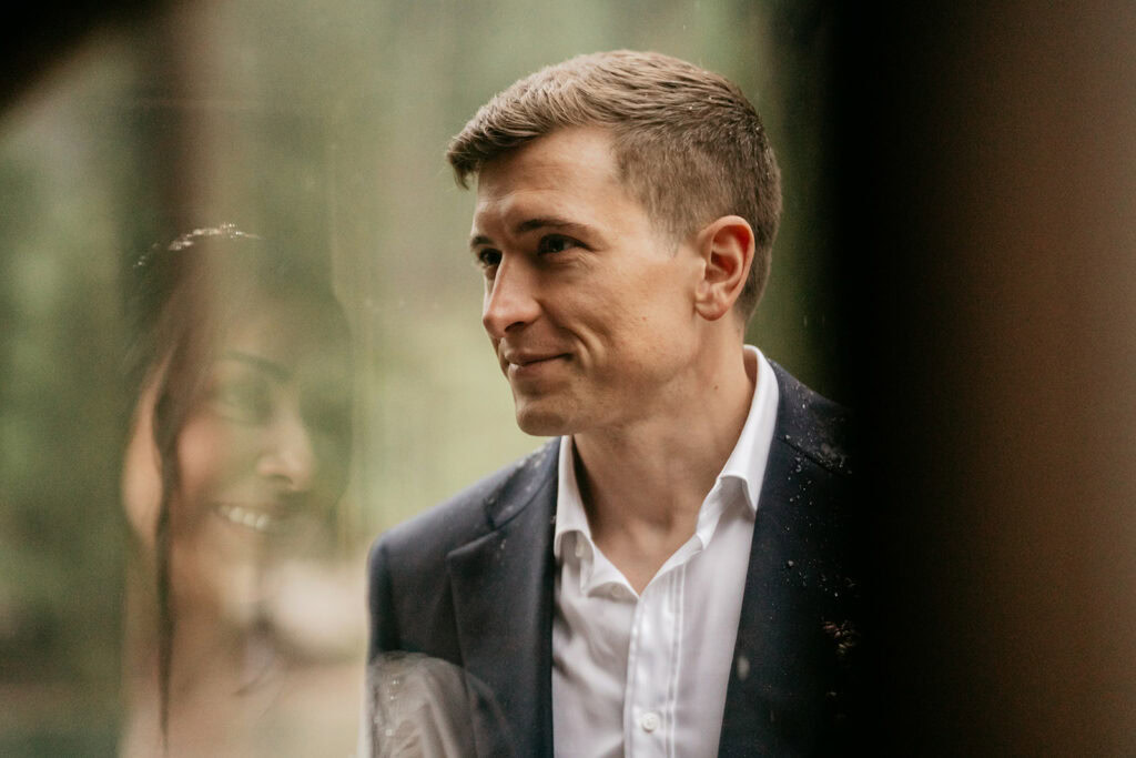 Man standing in suit with reflection in glass.