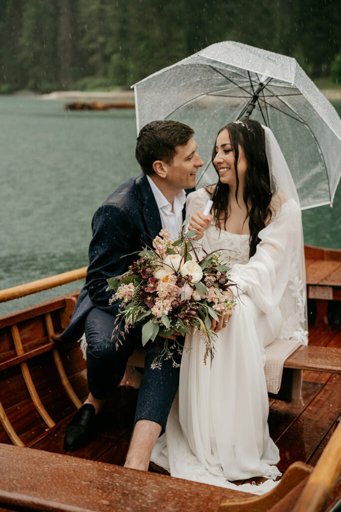 Couple in boat holding umbrella and flowers.