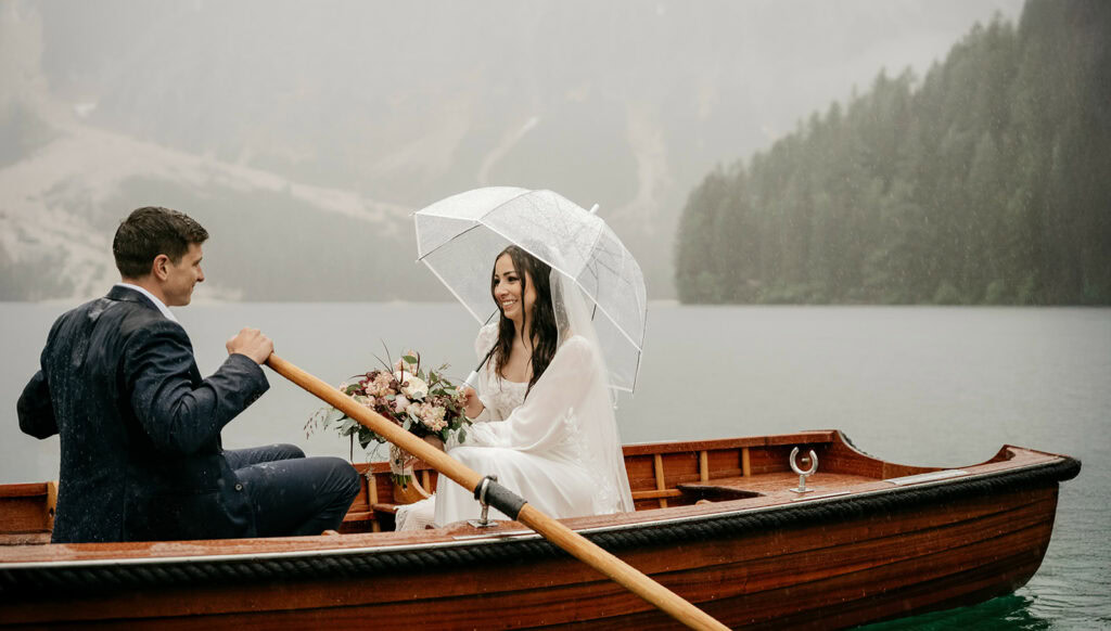 Couple in a boat, rain, umbrella, lake view.