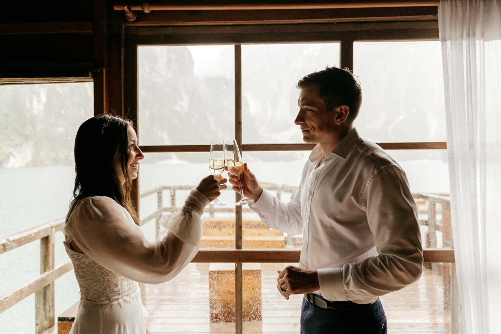 Couple toasting with champagne by lake view window.