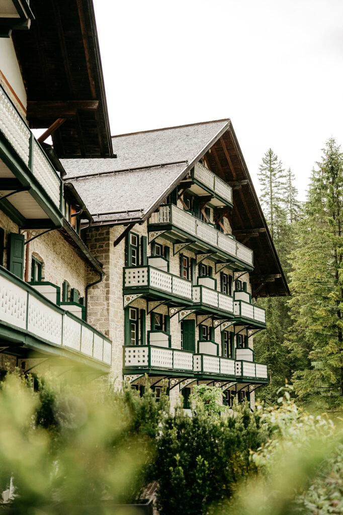 Stone building with green balconies and forest background.