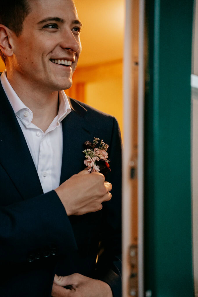 Smiling person wearing suit with floral boutonniere.