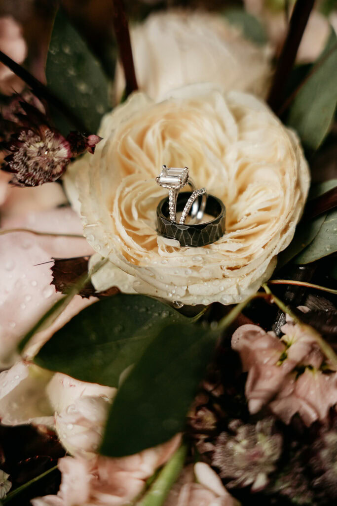 Wedding rings in white rose with greenery