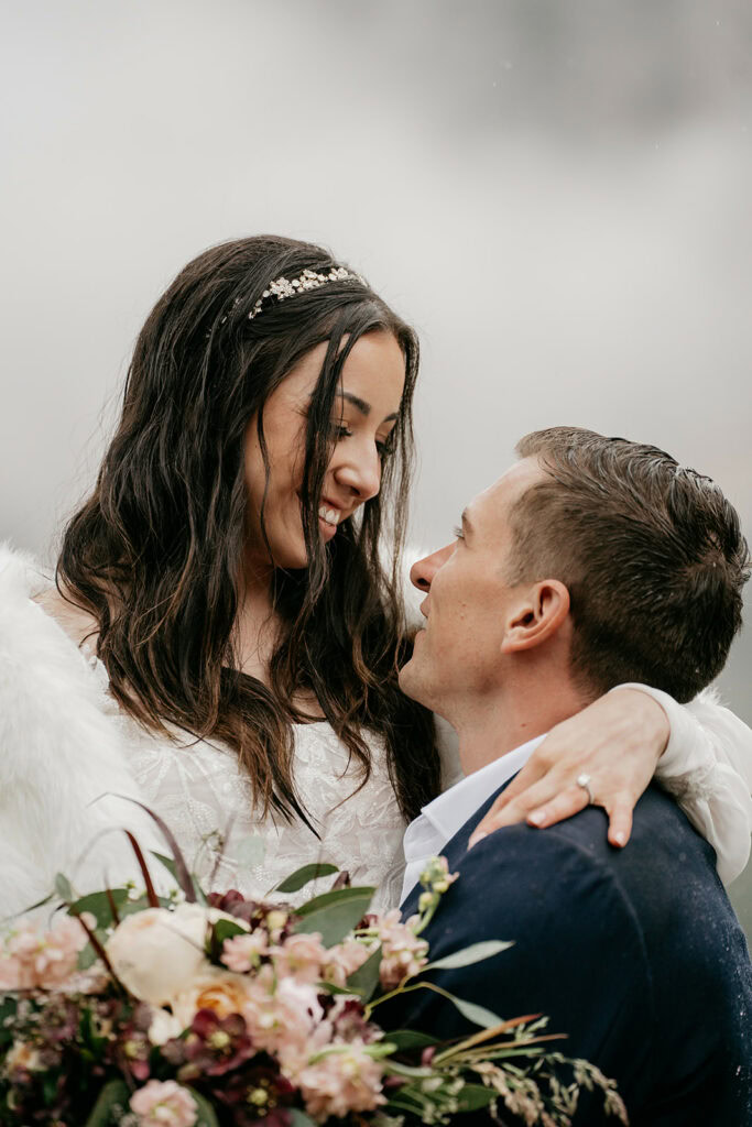 Bride and groom embracing with flowers.