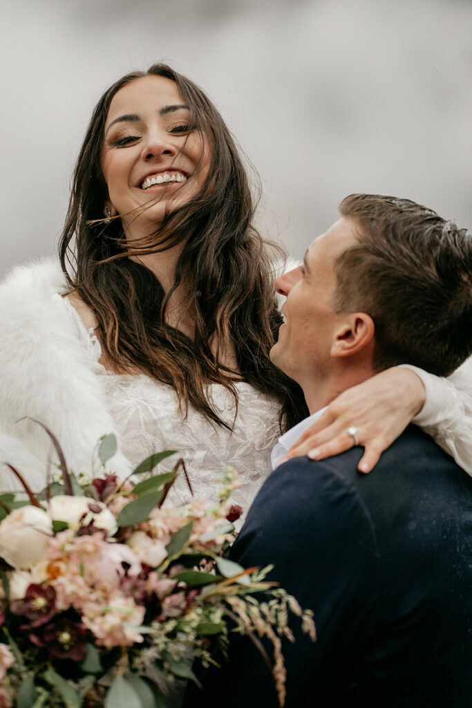 Happy couple embracing with flowers and smiles.
