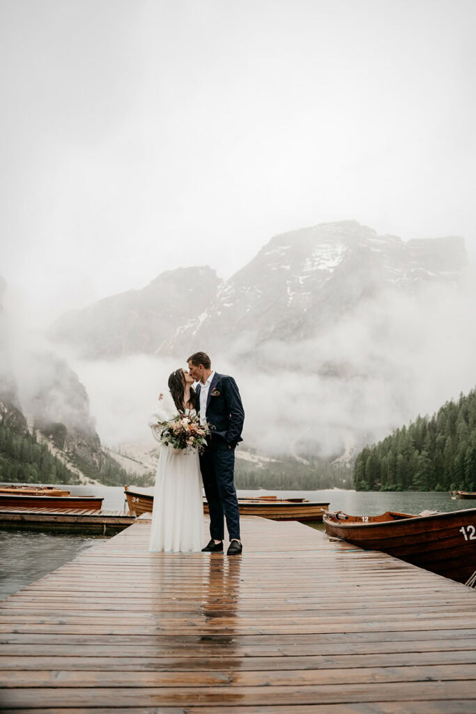 Couple kissing on dock by misty mountains