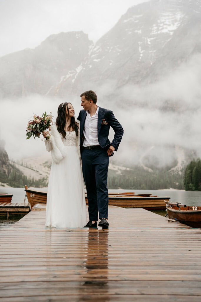 Bride and groom on dock with mountain backdrop.