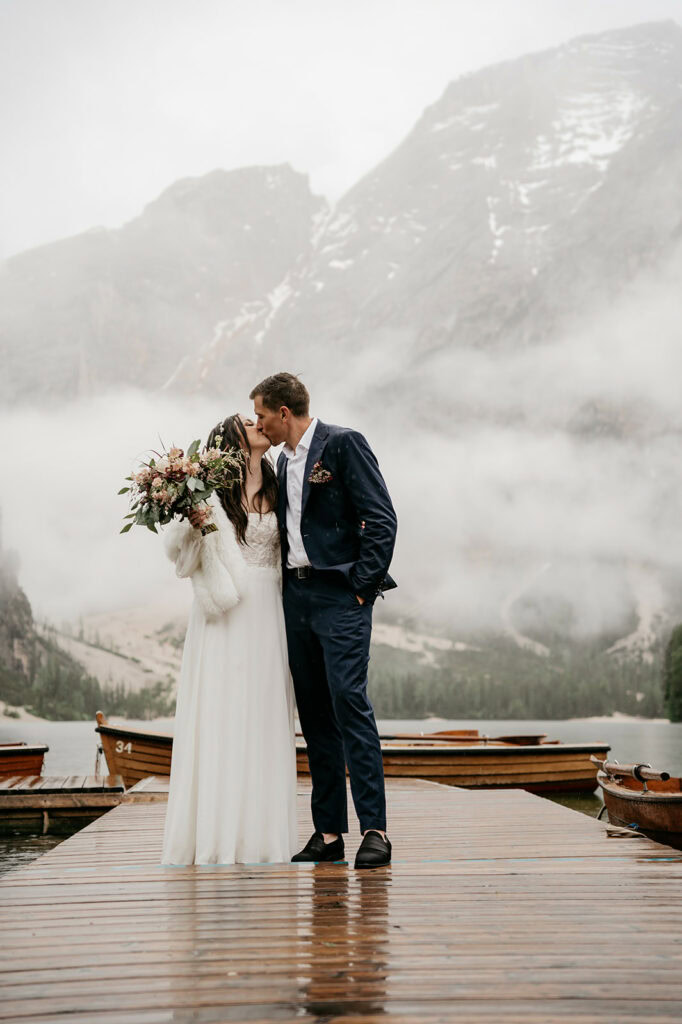 Bride and groom kissing on a foggy dock.