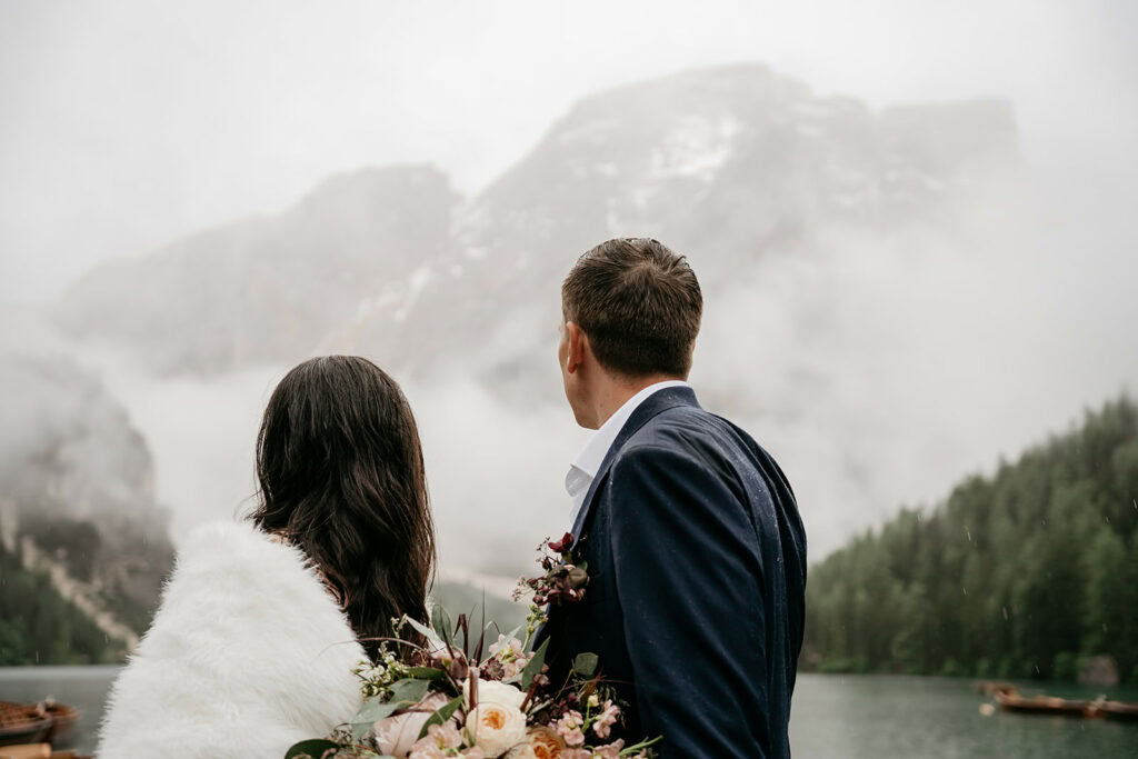 Couple admiring misty mountain landscape by lake.