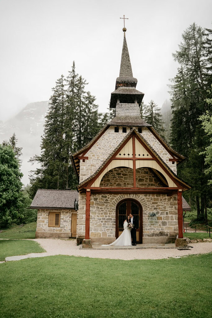 Rustic stone chapel surrounded by trees.