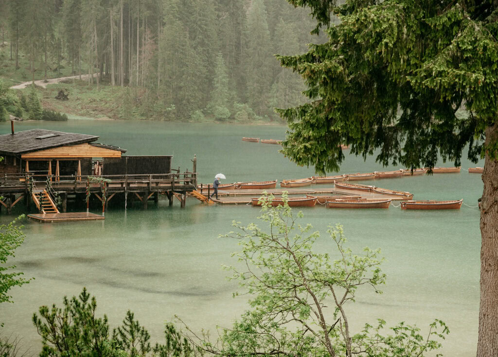 Lake with docked wooden boats and forested background.