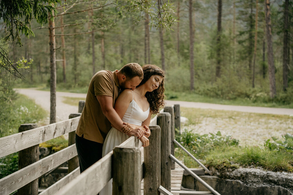 Couple embracing on a wooden bridge in forest.