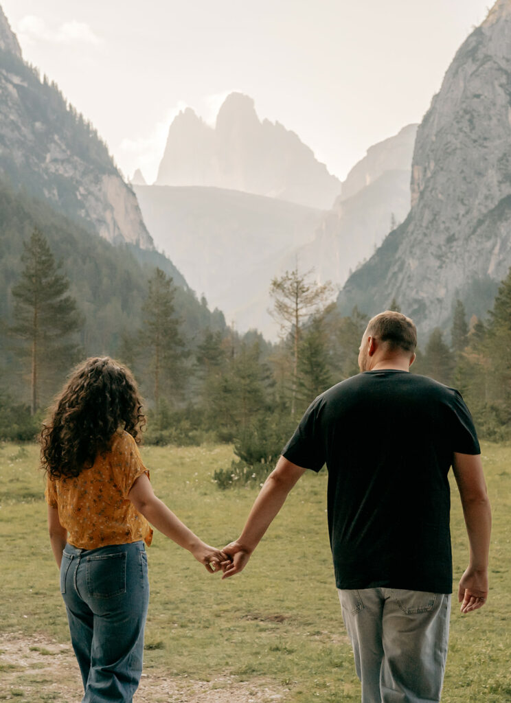 Couple walking hand in hand in scenic mountains.