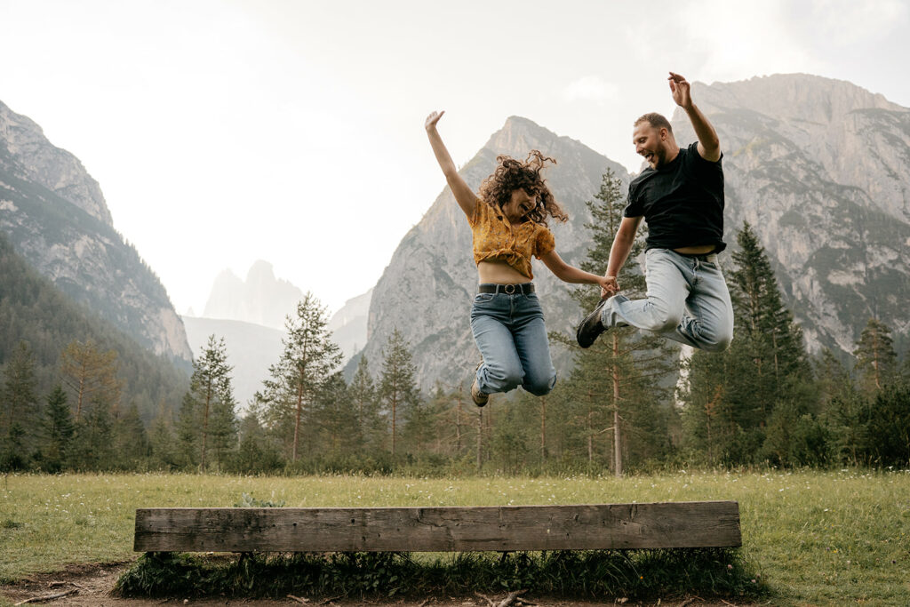 Couple jumping in mountain scenery joyfully.