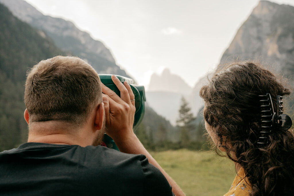 Couple sightseeing mountains with binoculars.