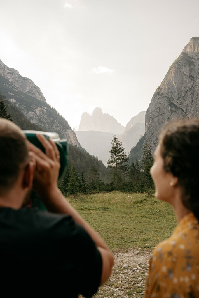 Couple enjoying mountain view with binoculars.
