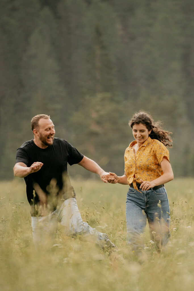 Couple running joyfully through grassy field.