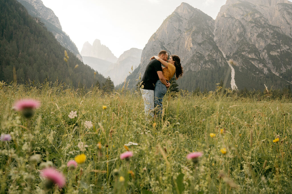 Couple embracing in mountain meadow landscape.