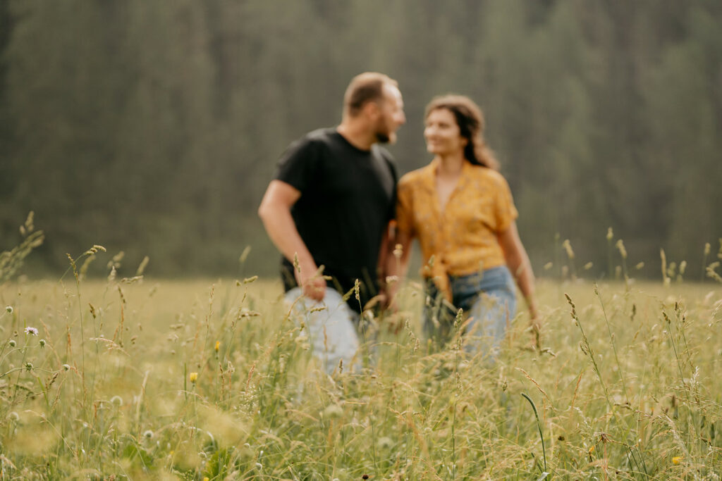 Couple walking in grassy field, blurred background.