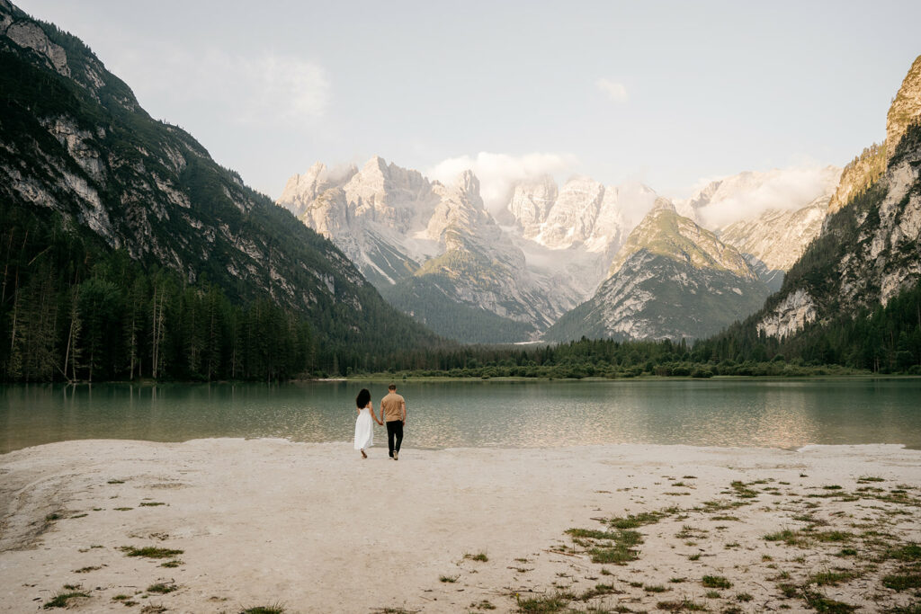 Couple walking by lake with mountain view.