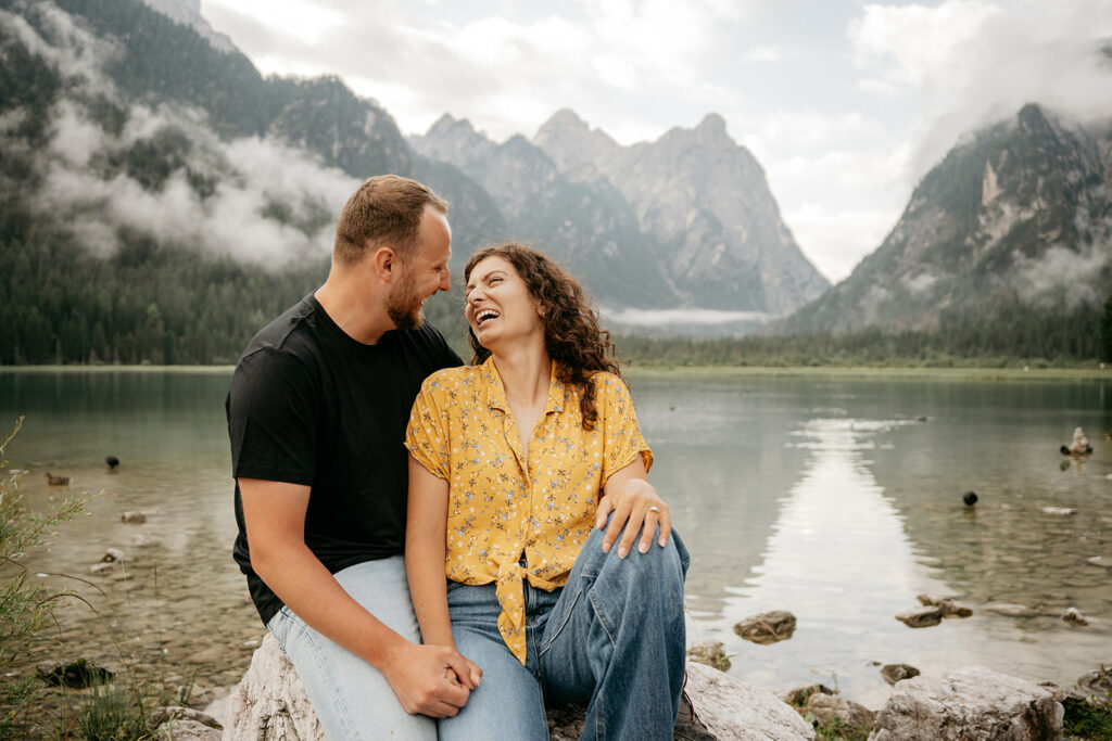 Couple laughing by mountain lake.